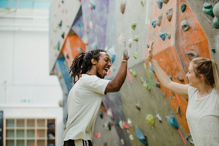 Two climbers high fiving in a climbing centre